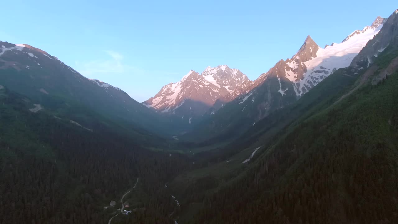 鸟瞰图，延时飞行在山峡。美丽的风景与雪山在绿色森林的背景。在山里旅行视频素材