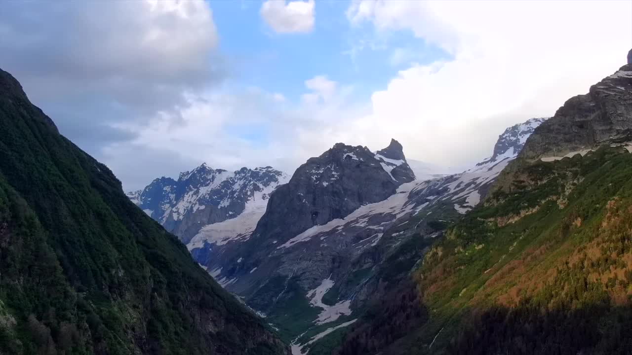 鸟瞰图，延时飞行在山峡。美丽的风景与雪山在绿色森林的背景。在山里旅行视频下载