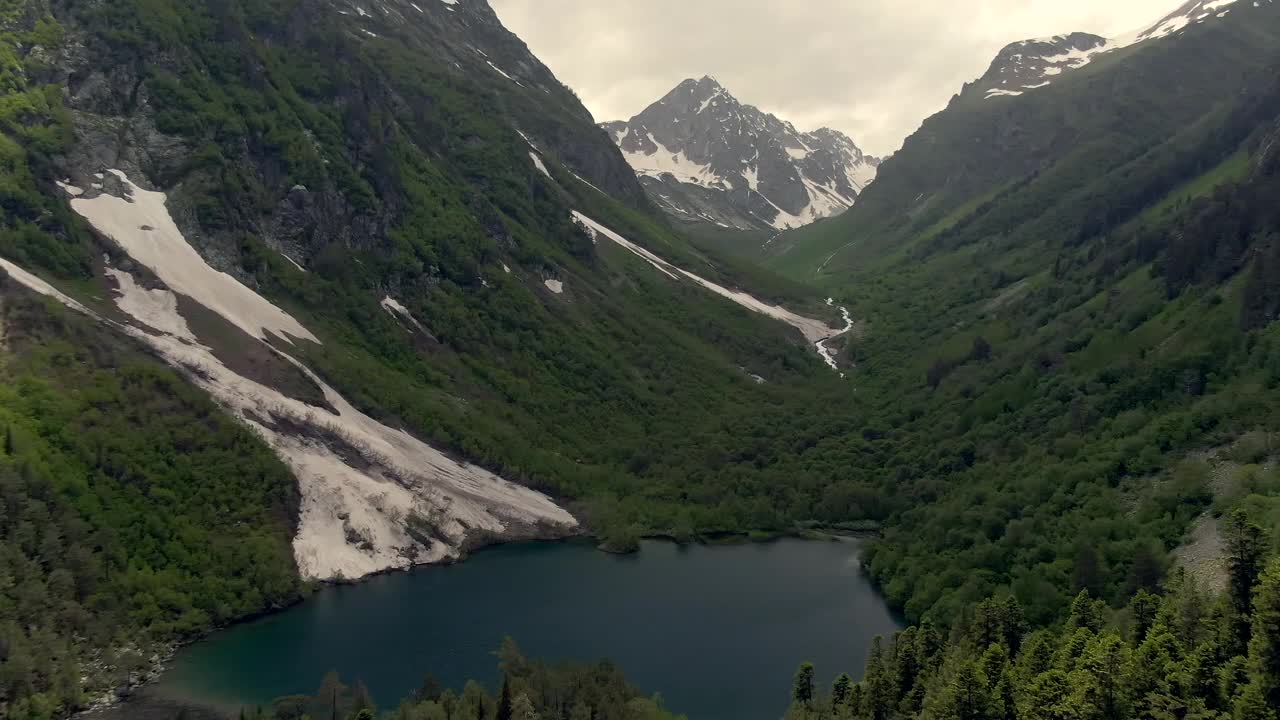 从空中俯瞰峡谷中的高山湖泊。蓝天白云映衬着美丽的山景。山里的娱乐视频下载