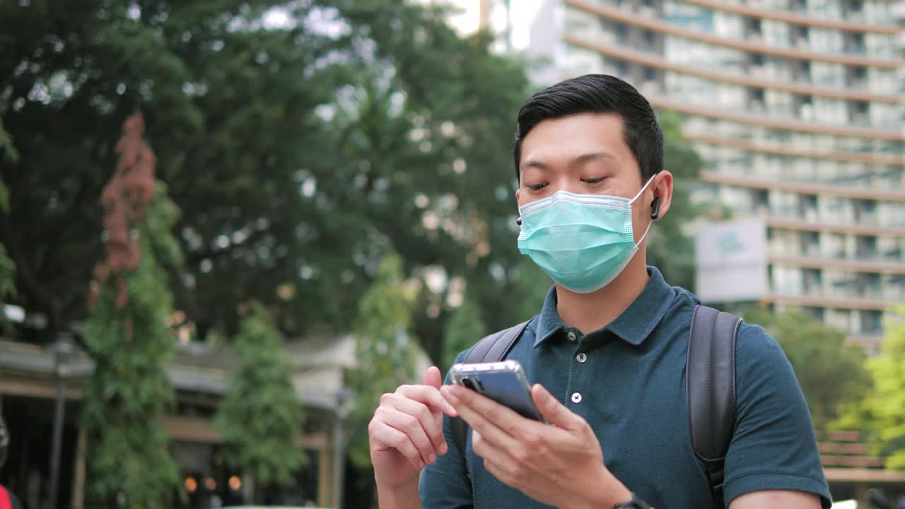 亚洲男子在医疗防护面具自拍视频通话在城市行走视频素材