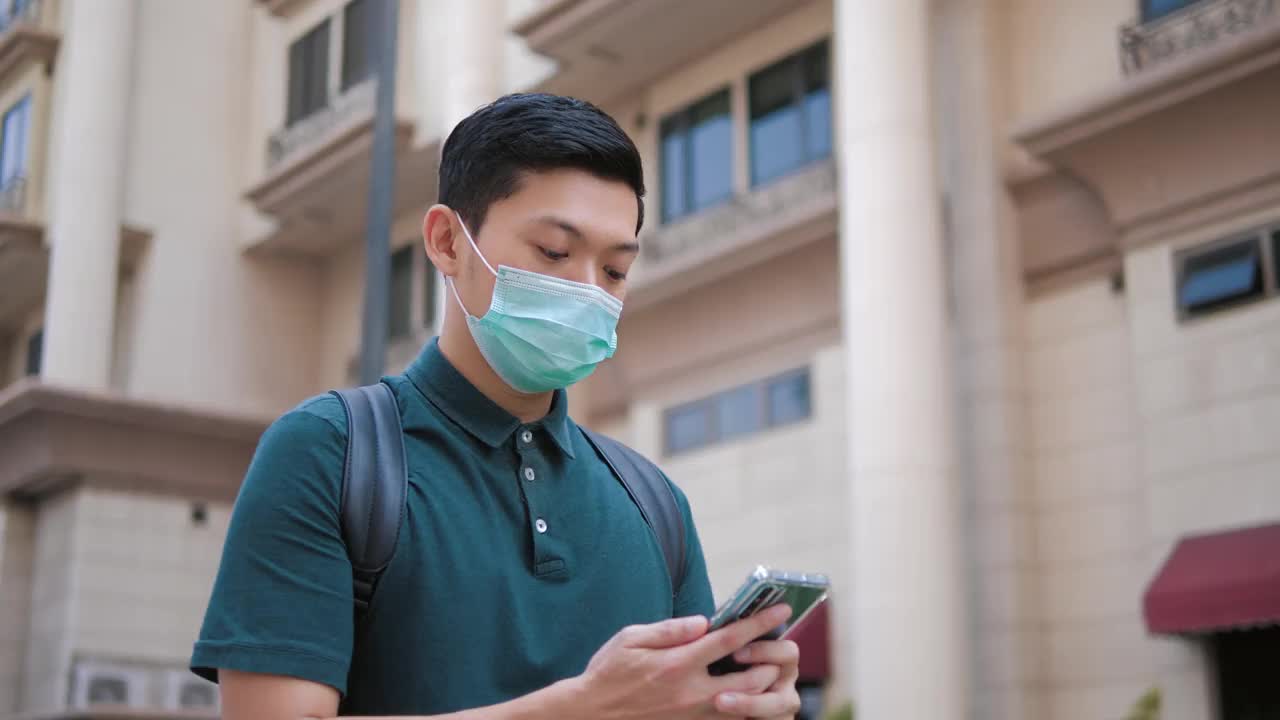 亚洲人戴着医用口罩，用手机上的导航应用程序视频素材