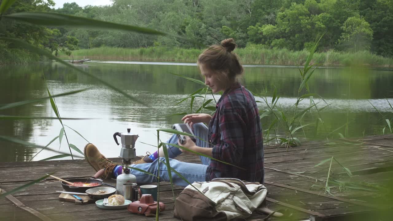 一个十几岁的女孩在河边的木码头上野餐视频素材