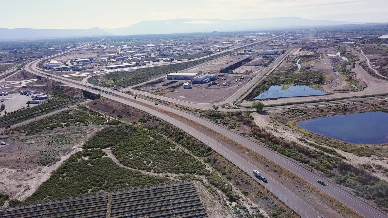 从州际公路上经过的汽车鸟瞰图，旁边的太阳能农场提供绿色，可再生能源到一个乡村科罗拉多镇视频素材