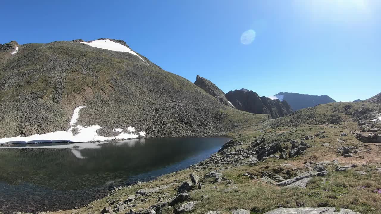 Schladming附近的奥地利阿尔卑斯山一个小湖的全景。这个湖被高山环抱着。山坡上有些雪。山坡是光秃秃的。阳光明媚的一天。无尽的山脉视频素材