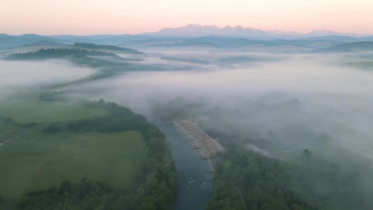 日出时分，无人机在松嫩山脉的Dunajec河上空的雾和云上飞行。波兰户外景观视频下载