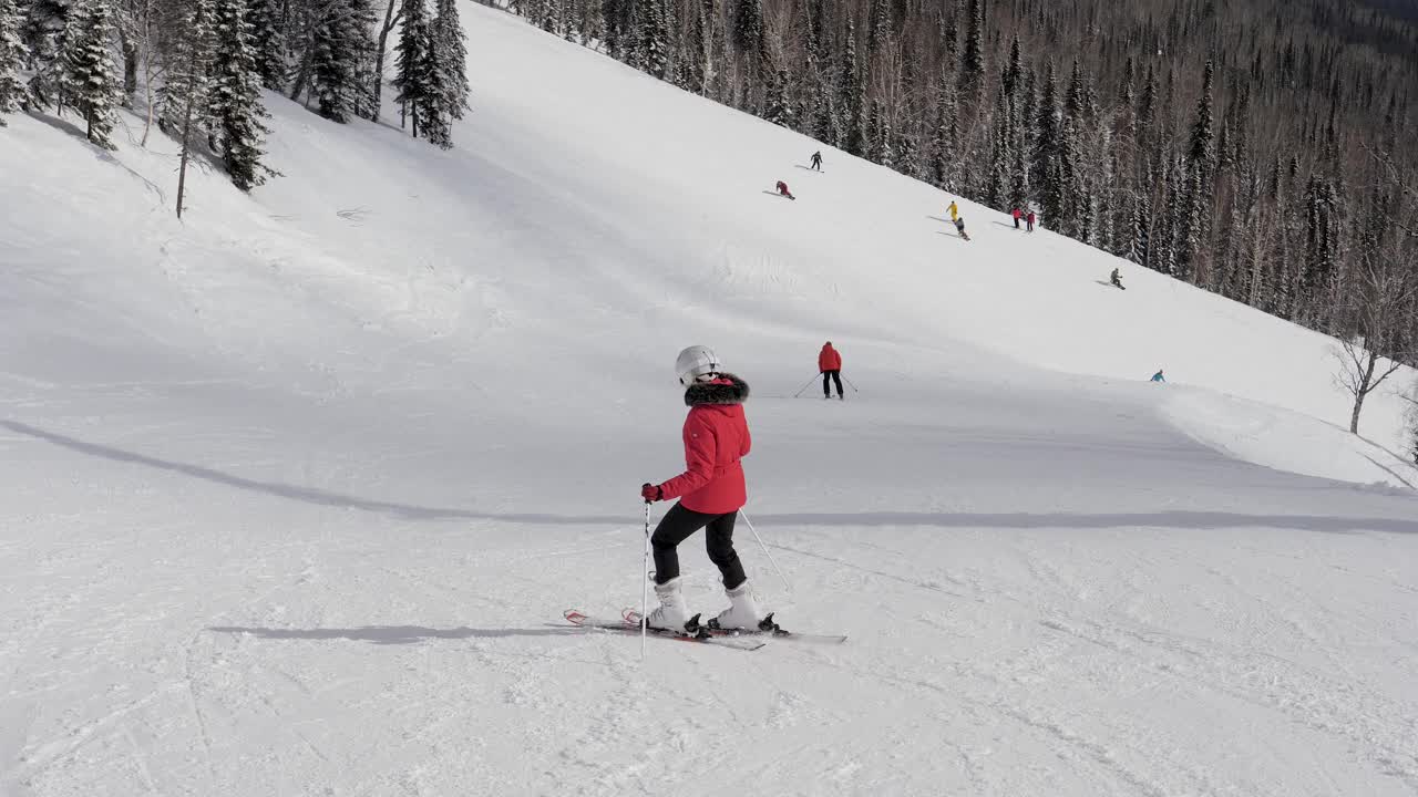 初学滑雪的人在冬天沿着山上跑道的斜坡滑雪视频素材