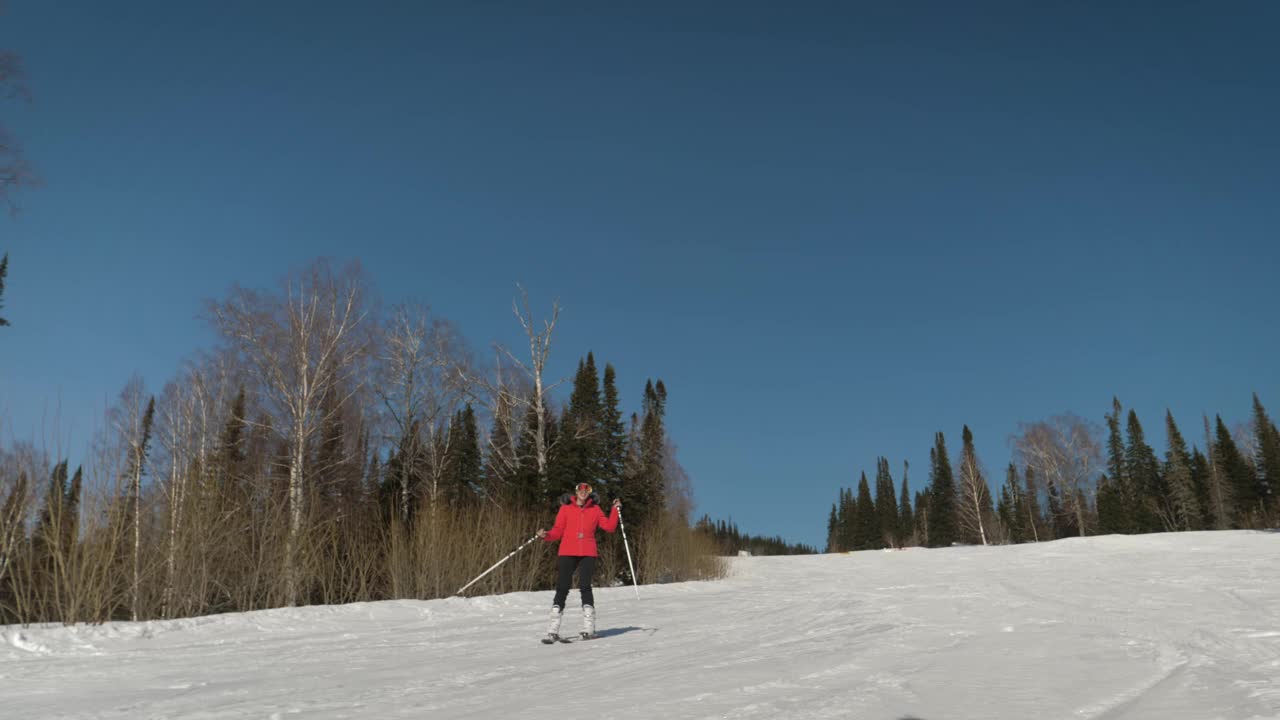 一个快乐的女人在滑雪场的雪道上滑雪，微笑着跳舞视频素材