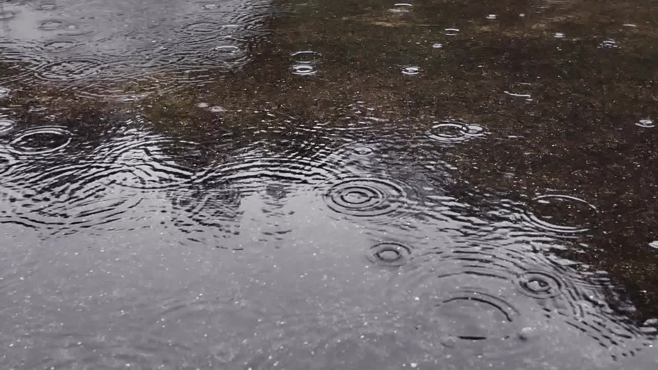 雨水落在柏油路上的大水坑里，淹没了道路。雨季的雨水落在混凝土地板上。视频素材