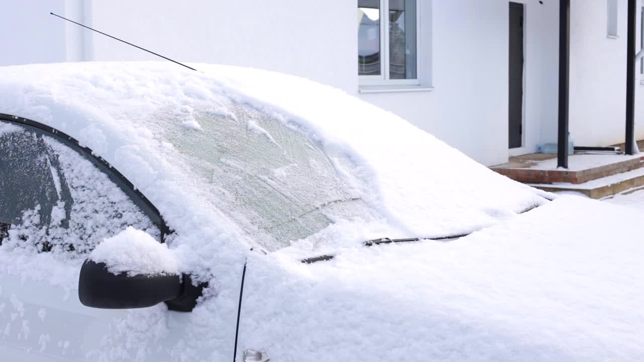 妇女用汽车清扫积雪。路上下雪了。司机清洁汽车视频下载