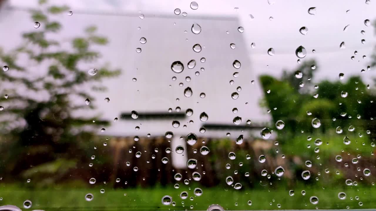 雨滴落在窗户上。玻璃上水滴的特写。夏天阵雨时，大雨滴打在窗玻璃上。4 k。视频素材