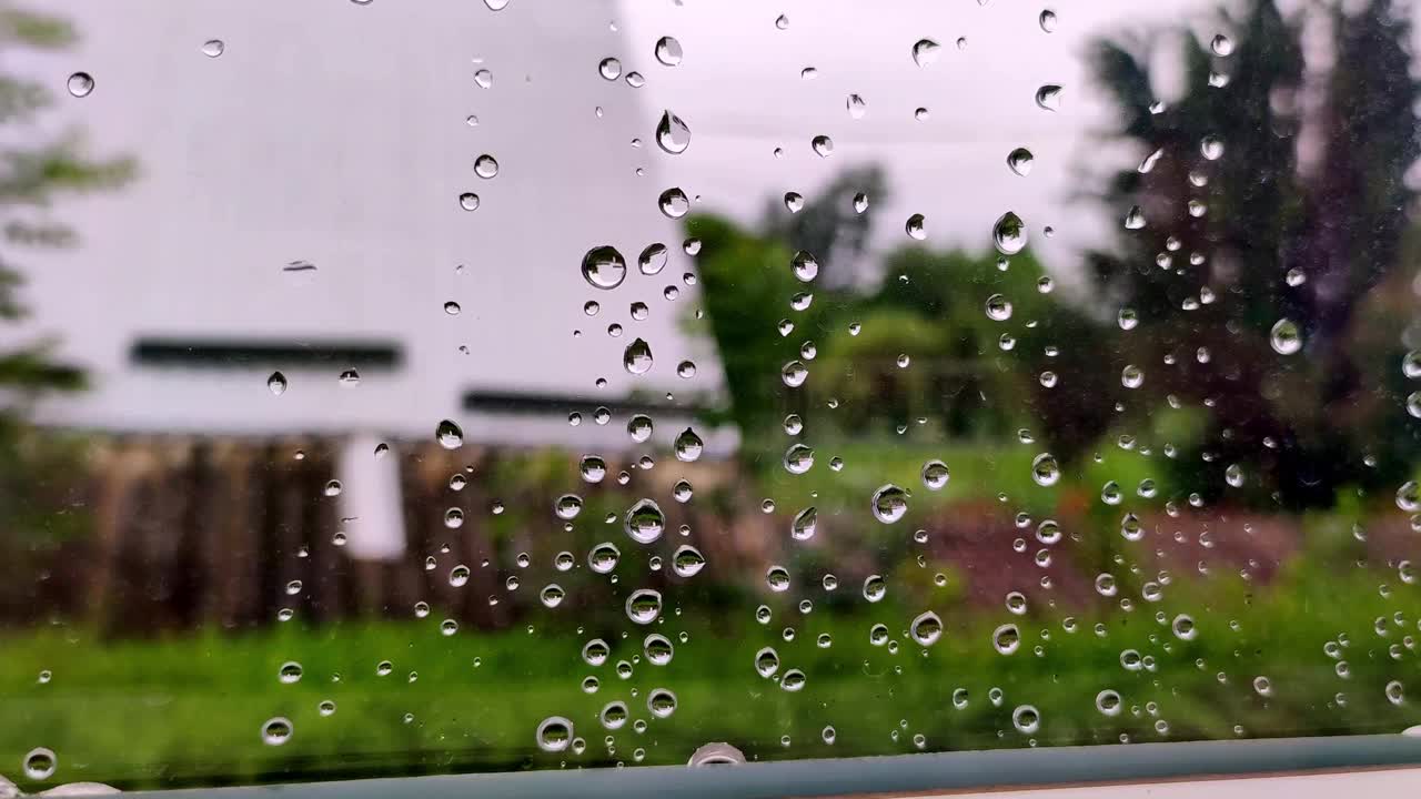 雨滴落在窗户上。玻璃上水滴的特写。夏天阵雨时，大雨滴打在窗玻璃上。4 k。视频素材