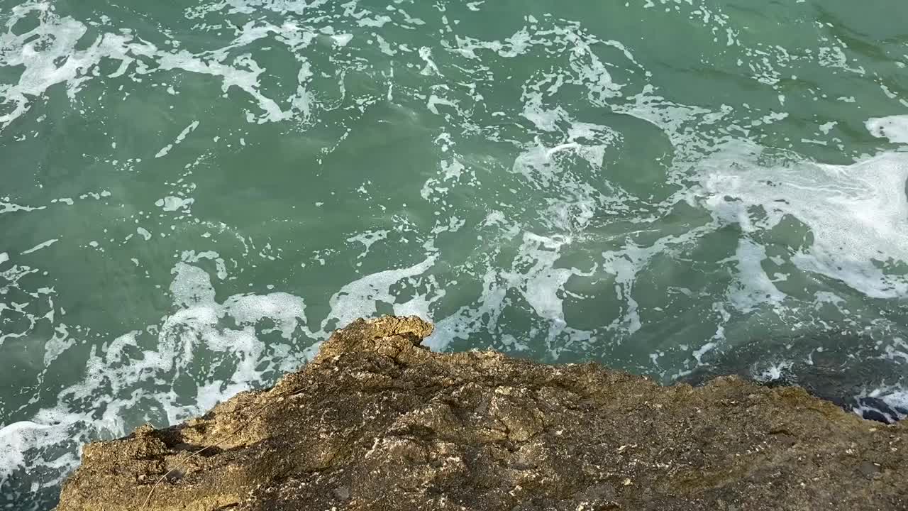 岩石海岸上的海浪。暴风雨的海景。蓝绿色海水表面。视频素材