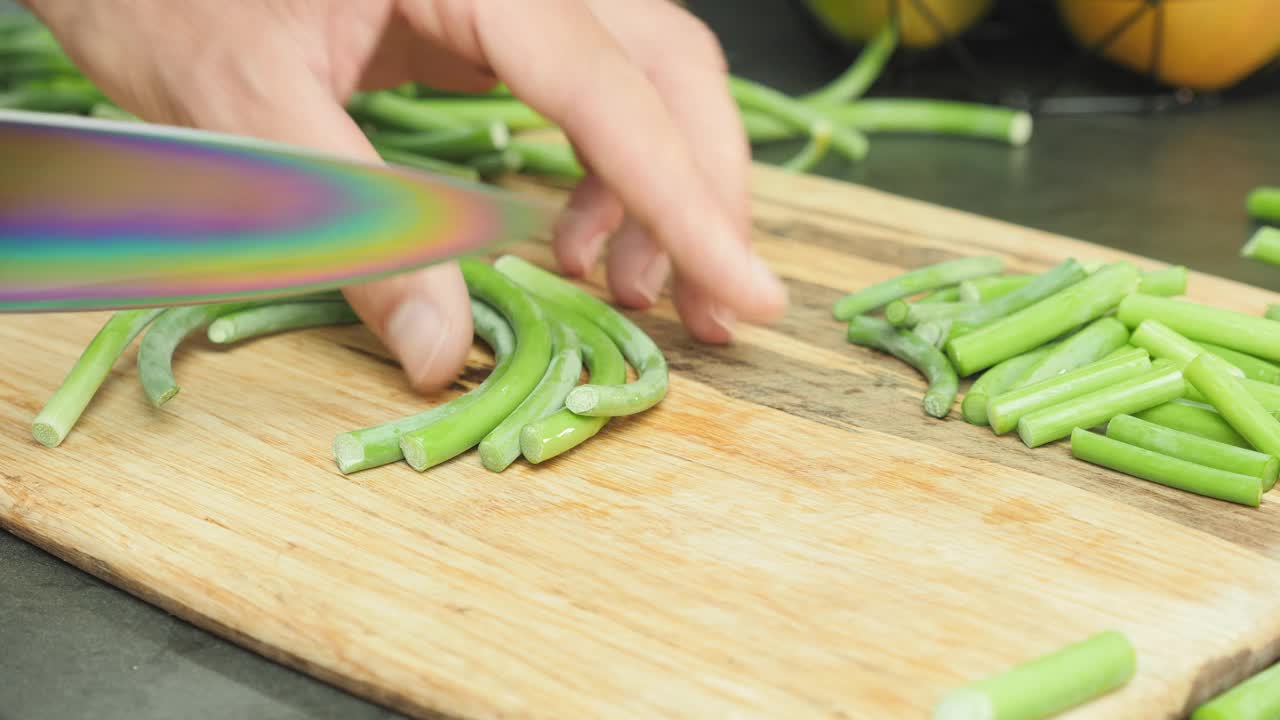 野生大蒜切在木砧板上。蒜苗切片。准备一束青豆视频素材