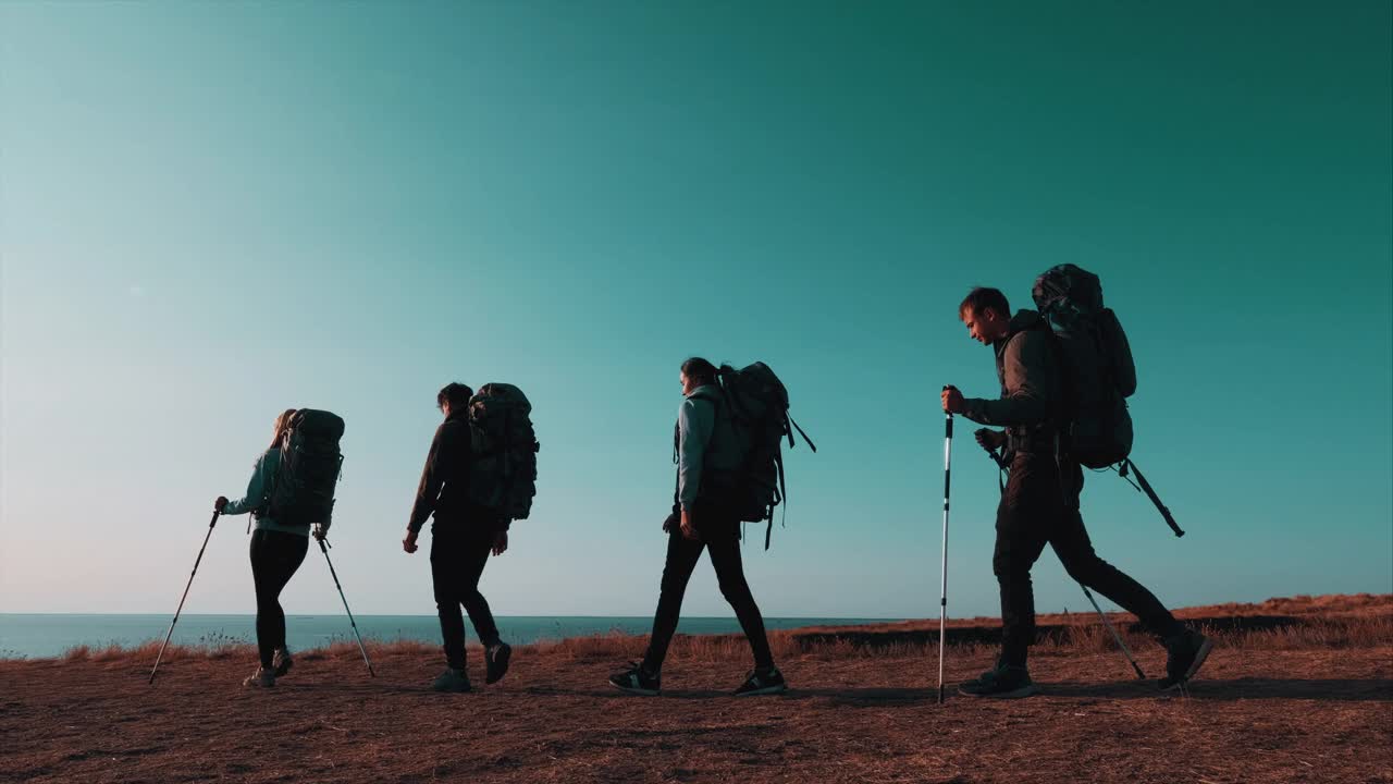 四个背着背包的旅行者在海边散步。慢动作视频素材