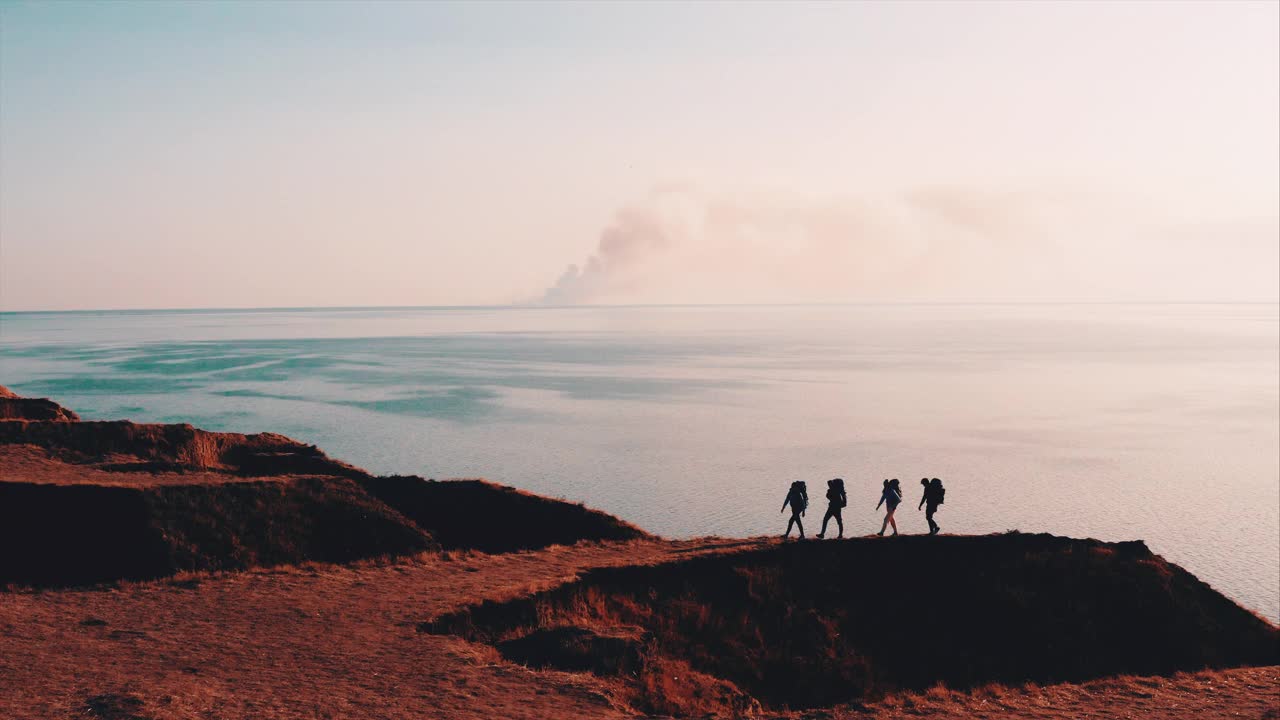 四名游客背着背包走在山上的海景上视频素材