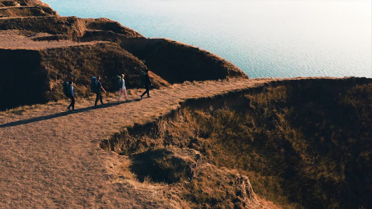 四名游客背着背包走在海边的山顶上视频素材