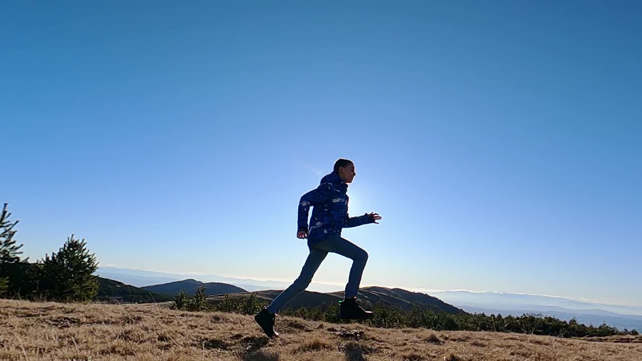 快乐的男孩在大自然中奔跑跳跃。快乐和平的童年视频素材