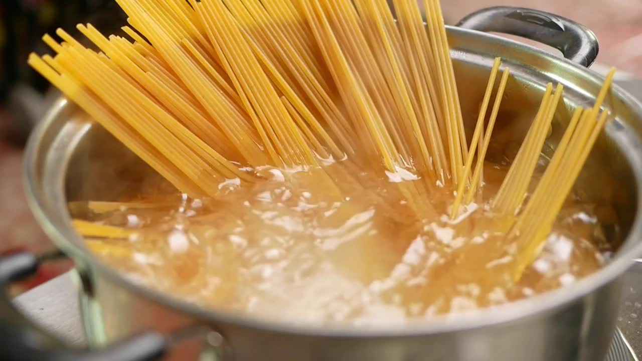 生意大利面正在厨房的锅里用沸水煮熟。健康的意大利食物和烹饪概念。视频素材