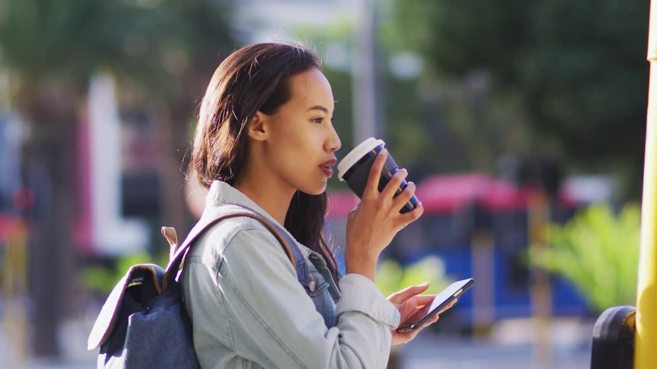 亚洲女人拿着智能手机喝着外卖咖啡视频素材