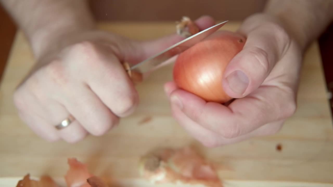 男人的手正在剥洋葱。准备做饭。视频素材