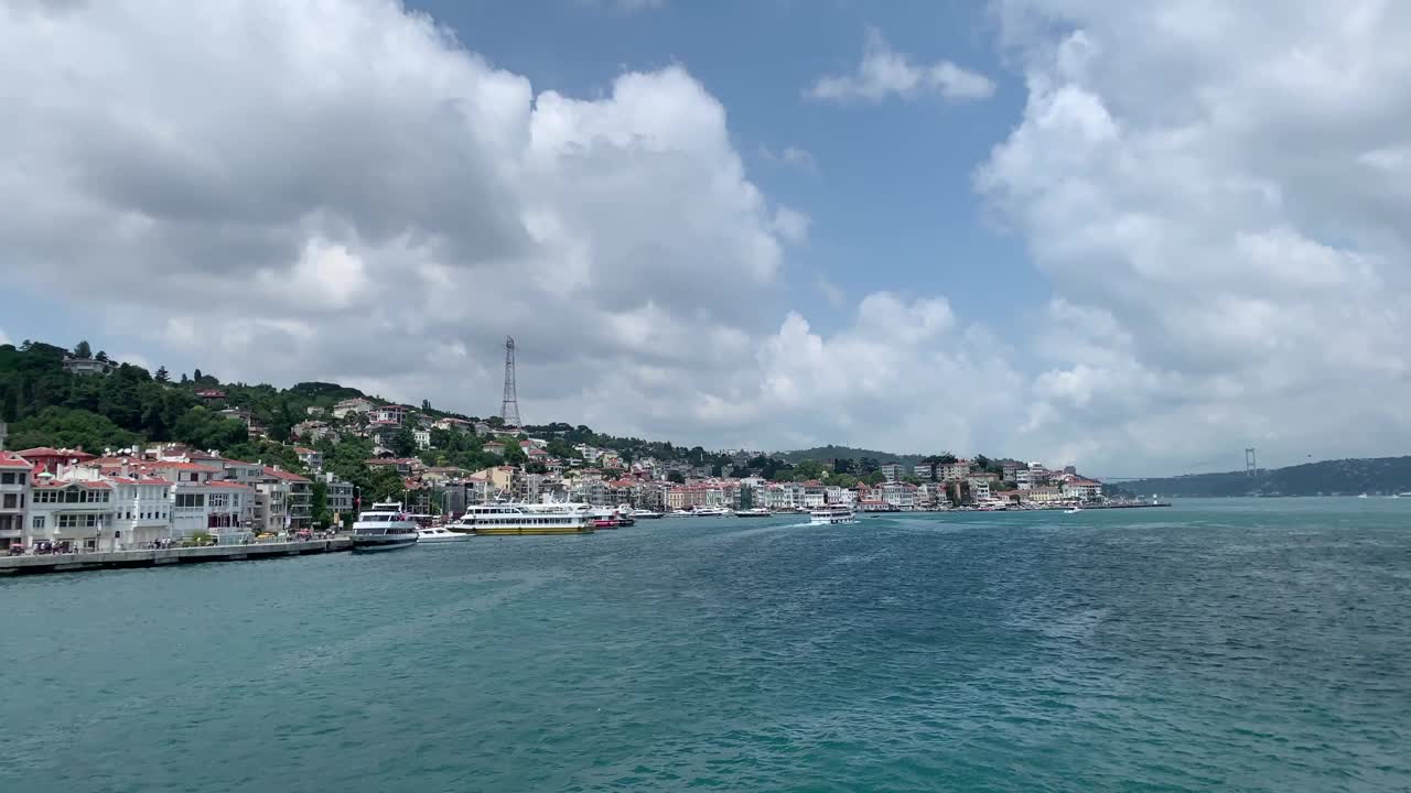 一艘游船经过博斯普鲁斯海峡，经过伊斯坦布尔名为“Kurucesme”和“Arnavutkoy”的高档社区。这是一个美丽的景色在一个阳光明媚的夏天。视频素材