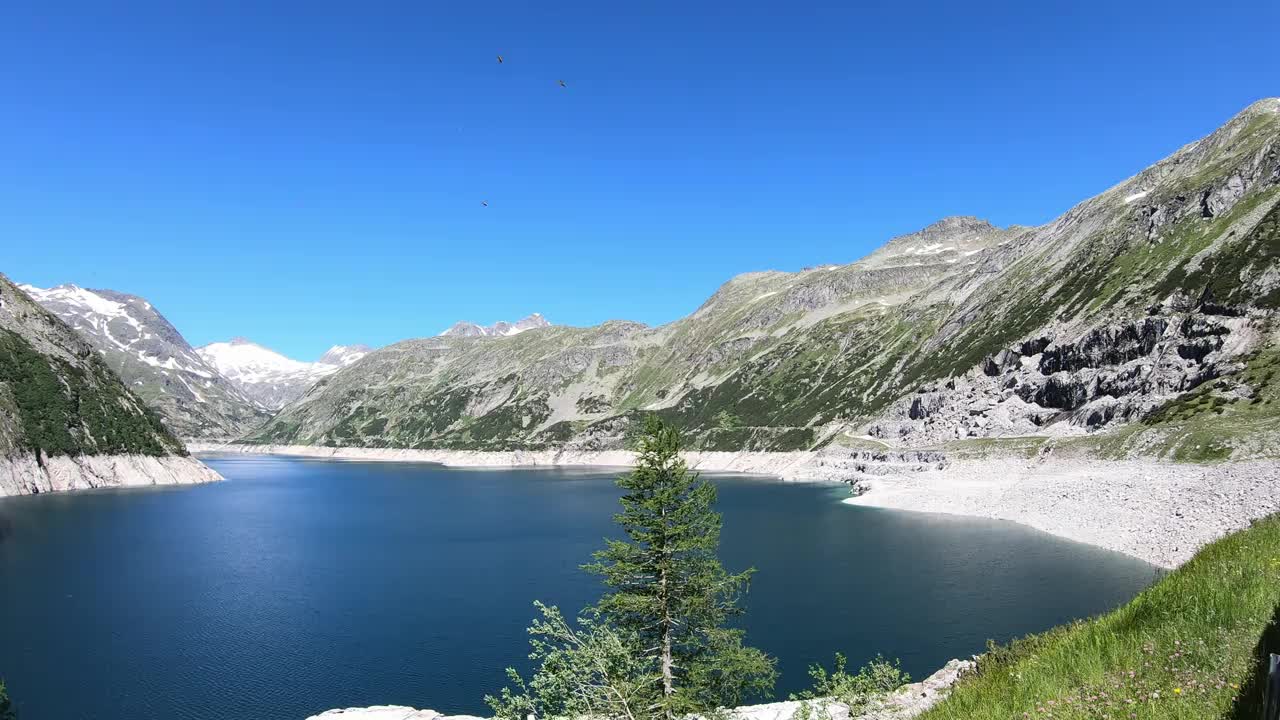 全景式的人工湖在科隆布雷因大坝在卡林西亚，奥地利。大坝被高山积雪覆盖的山峰包围着。陡峭的斜坡。这个湖是深蓝色的。自然能源视频素材