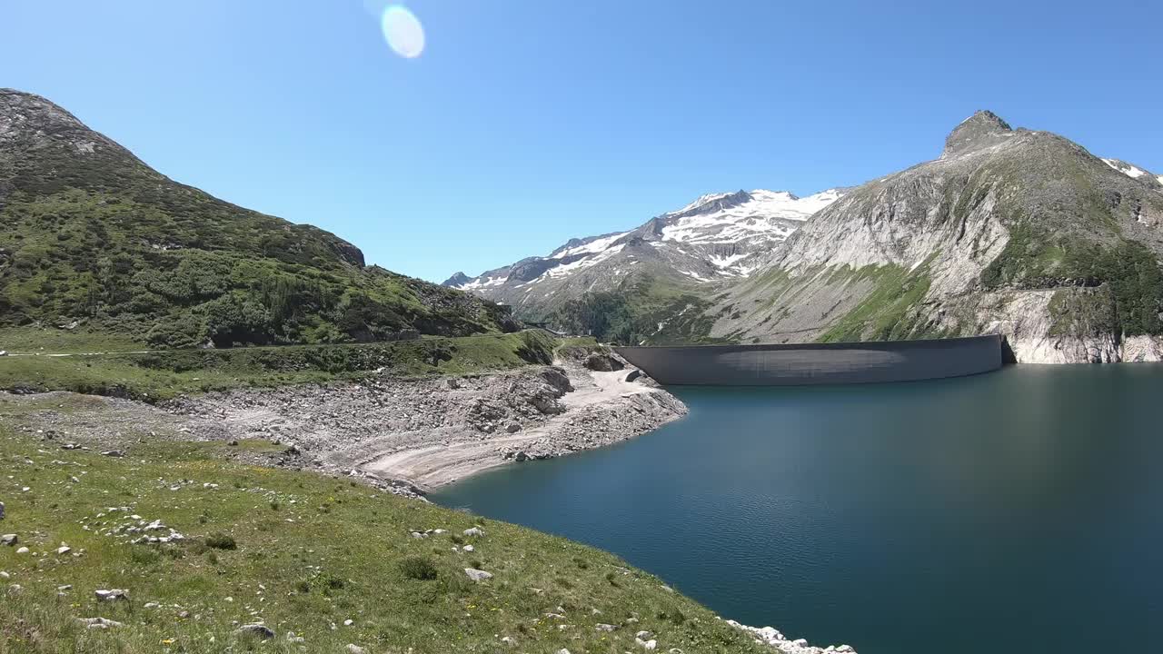 全景式的人工湖在科隆布雷因大坝在卡林西亚，奥地利。大坝被高山积雪覆盖的山峰包围着。陡峭的斜坡。这个湖是深蓝色的。自然能源视频素材