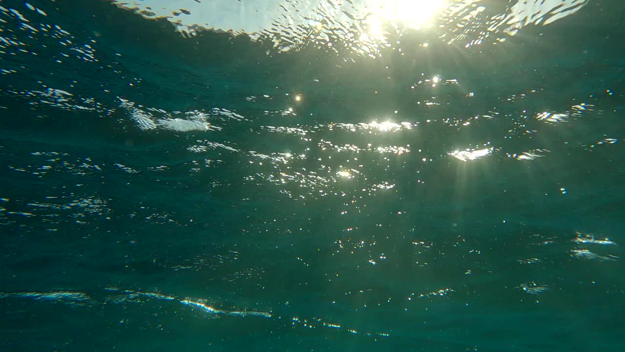 水面与波浪上的日落(水下拍摄)。自然背景与阳光在水面上闪烁。海面反射阳光的纹理。背光(Contre-jour)视频素材