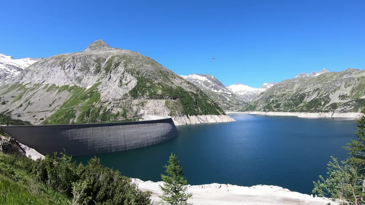 全景式的人工湖在科隆布雷因大坝在卡林西亚，奥地利。大坝被高山积雪覆盖的山峰包围着。陡峭的斜坡。这个湖是深蓝色的。自然能源视频素材