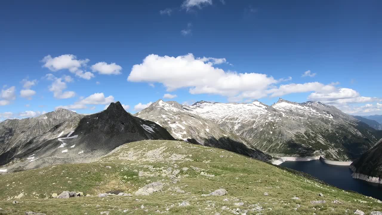 全景式的人工湖在科隆布雷因大坝在卡林西亚，奥地利。大坝被高山积雪覆盖的山峰包围着。陡峭的斜坡。这个湖是深蓝色的。自然能源视频素材