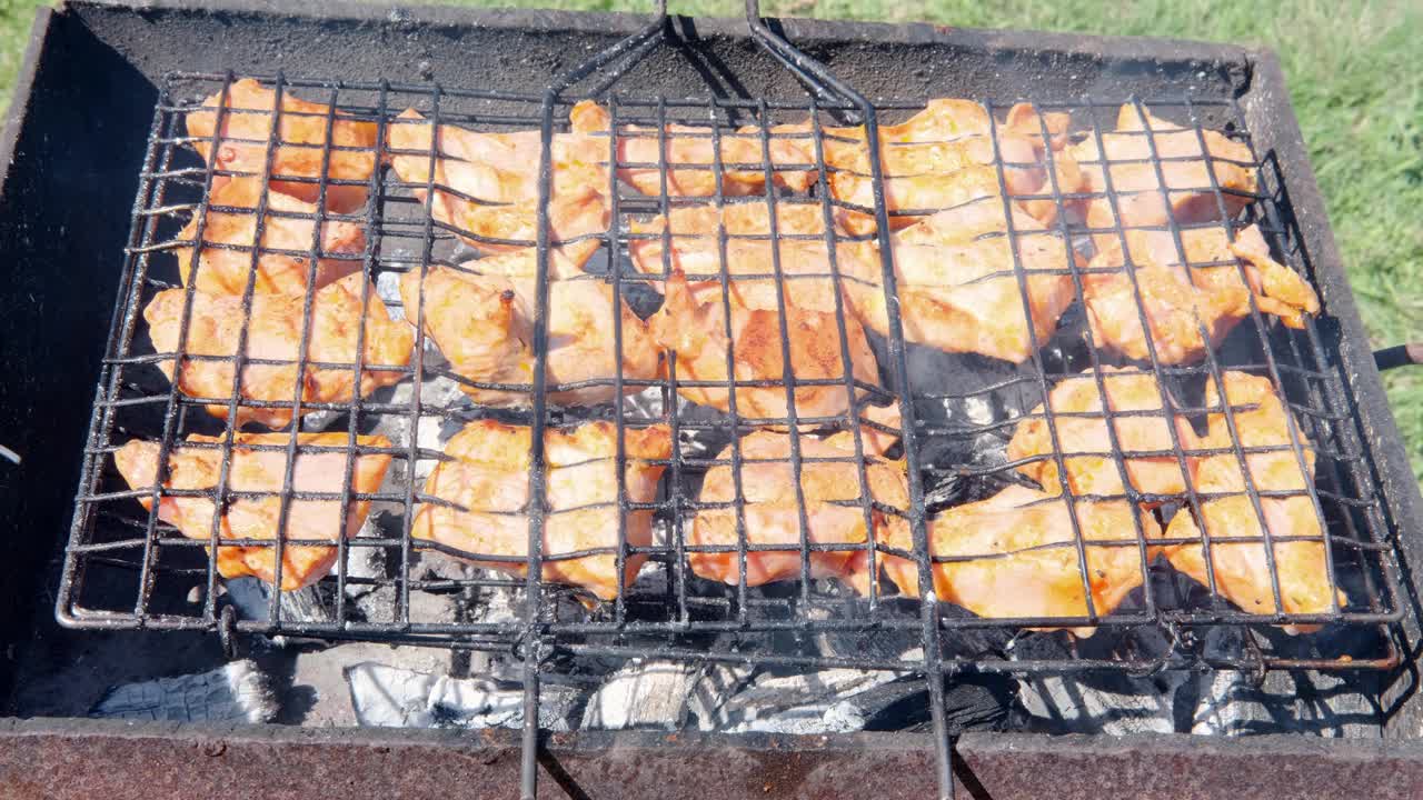 在炭火上烧烤多汁的肉，有火焰和烟雾。户外烧烤架视频素材