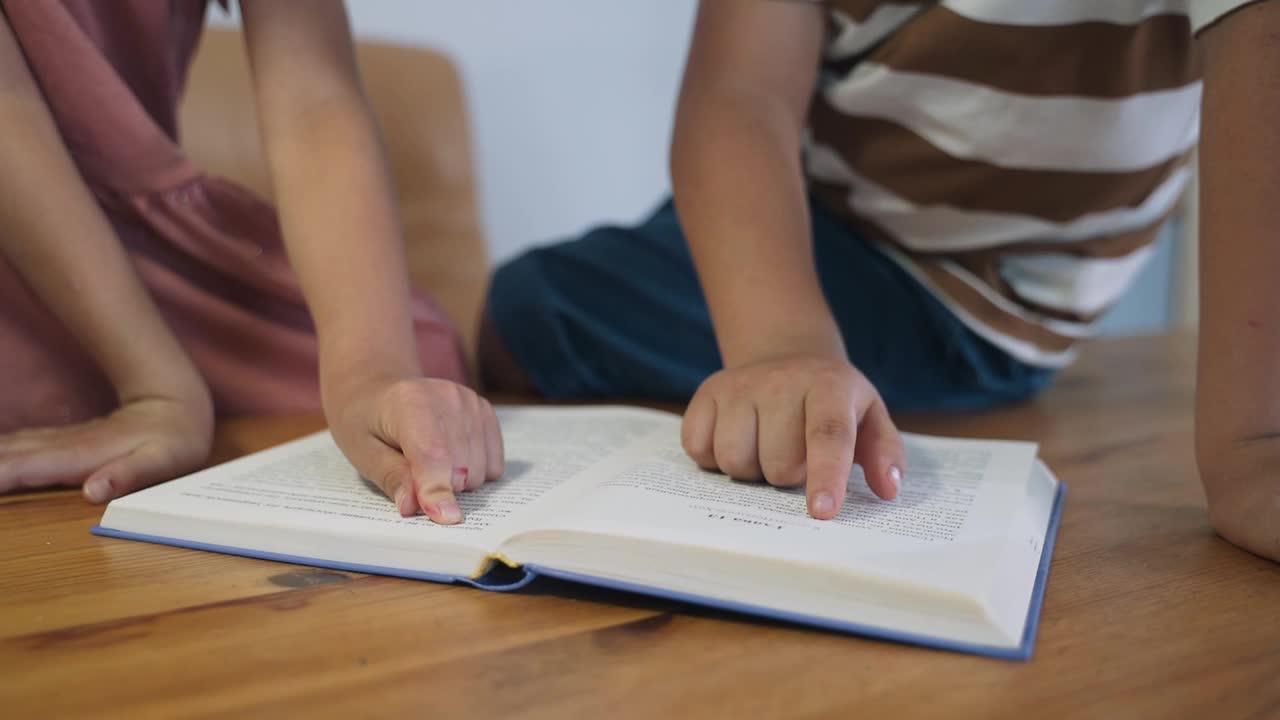 一个男孩和一个女孩正坐在桌子上看书。孩子们正在做作业。家庭教育。闭关锁国则。摧毁孩子们的教训。慢动作视频下载