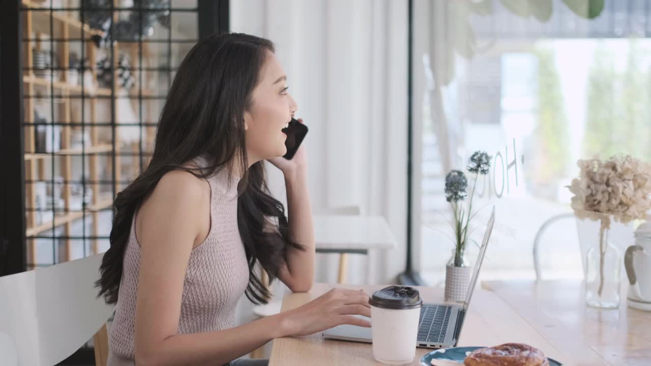 年轻的亚洲女子在咖啡店用手机打电话，在咖啡馆交谈视频素材