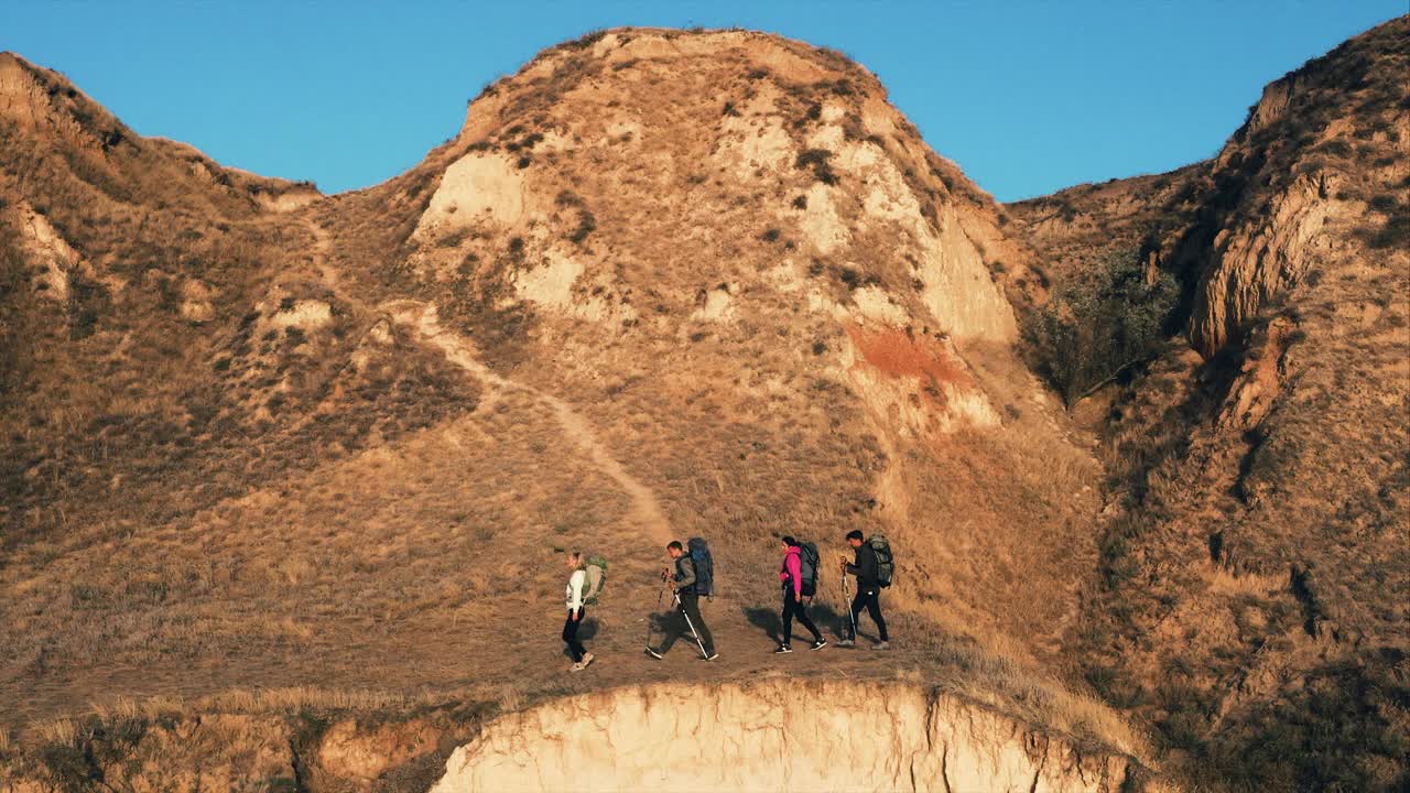 这四个人背着背包在沙山徒步旅行视频素材