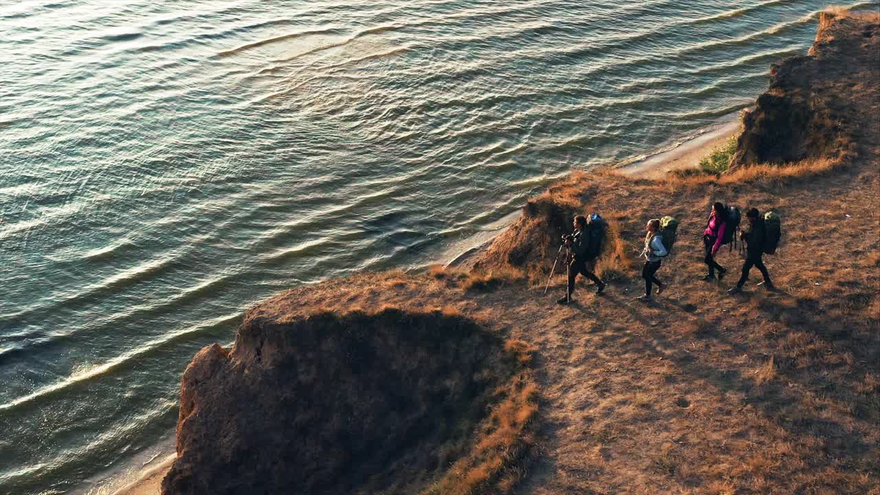 背着背包在海边的沙岩上行走的游客视频素材