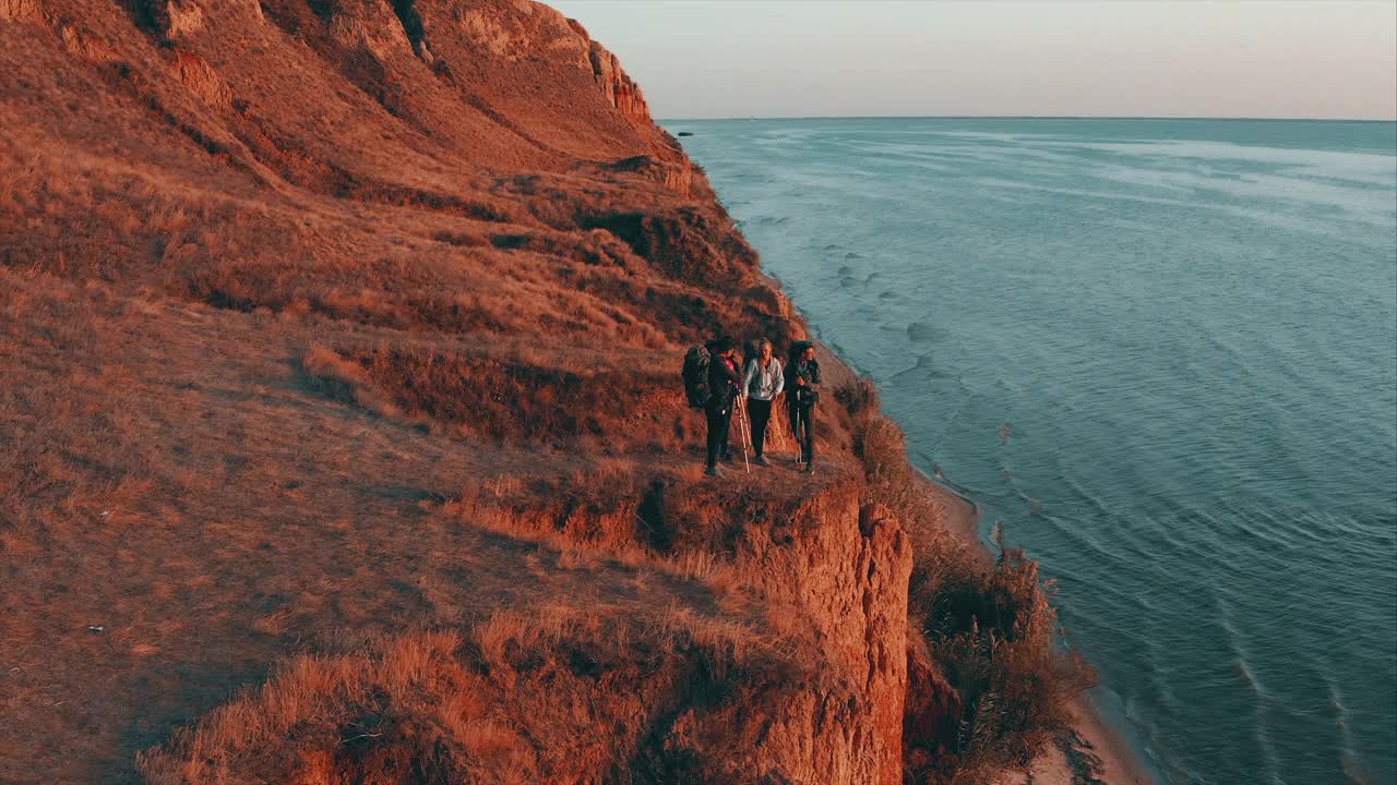 背着背包的旅行者站在海边的沙岩上视频素材