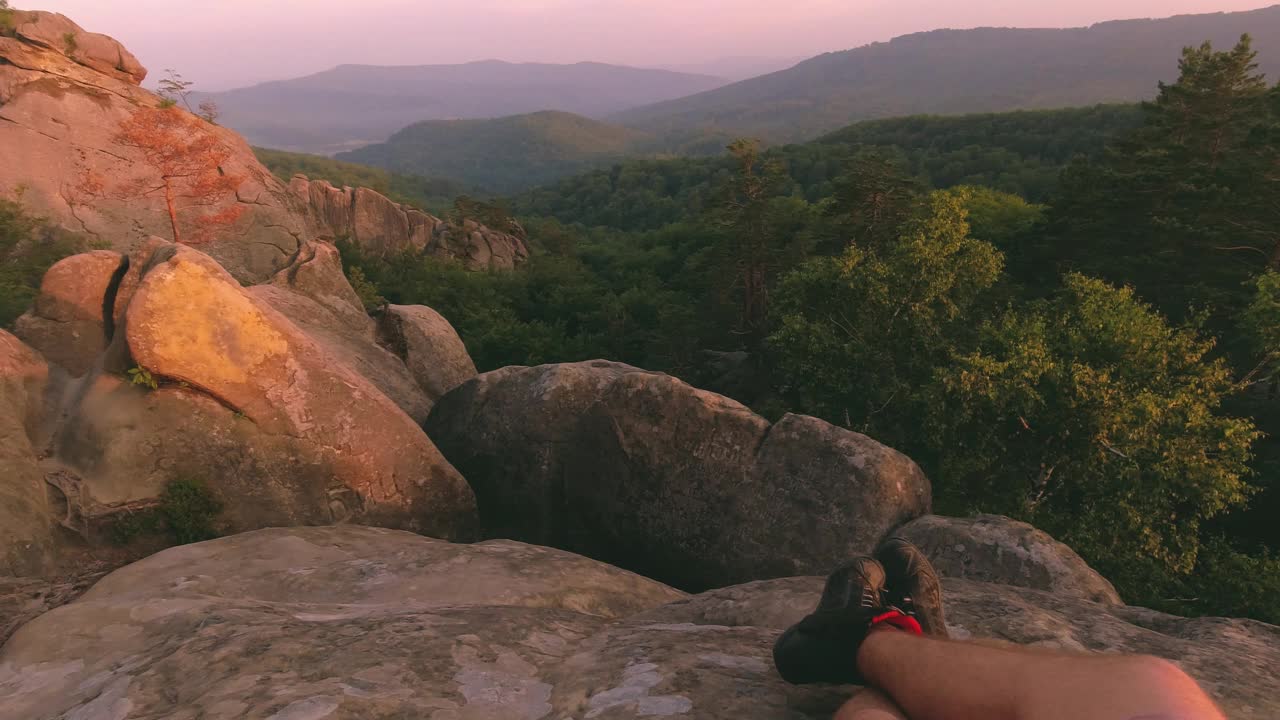 4k POV观看日落，脚在靴子休息的旅行者，观看在喀尔巴阡山脉的大岩石Dovbush，全景运动视频素材