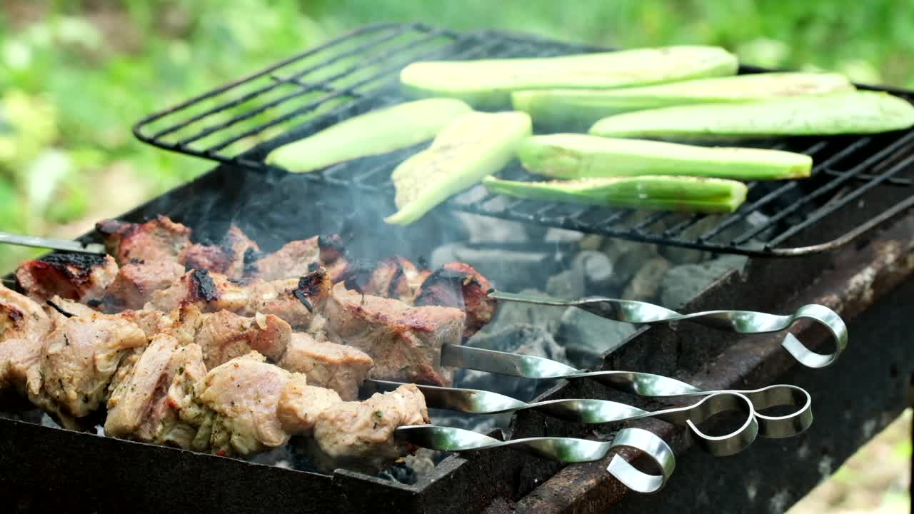 在户外用金属串和蔬菜做烤肉。传统的东方菜肴腌制烧烤肉在木炭和火焰上烧烤。烤猪肉，羊肉，烤肉串，烤肉串。街头食品视频素材