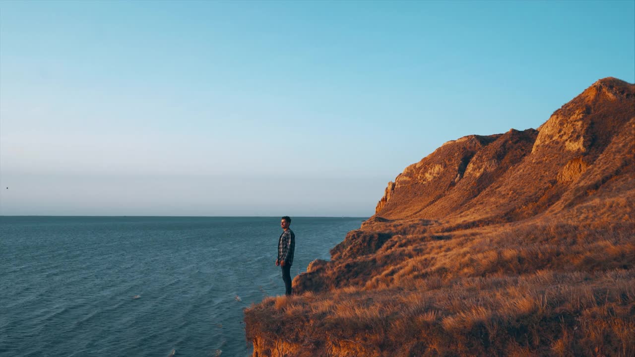 英俊的男子站在山崖上的海景视频素材