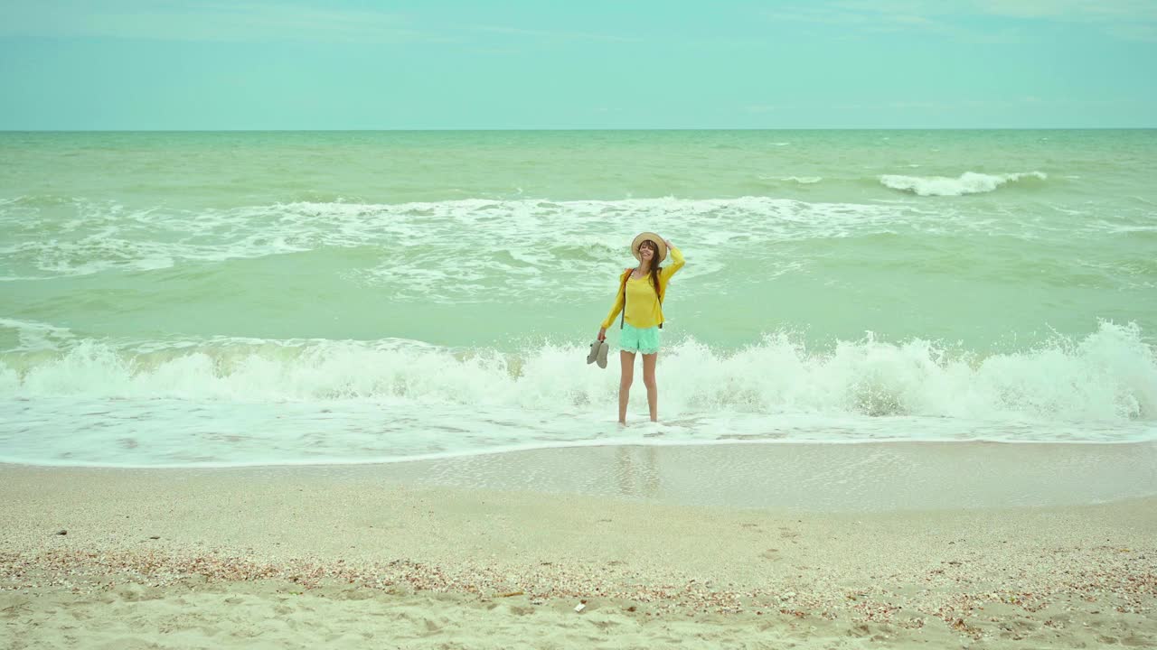 女人喜欢在刮风暴风雨的日子里漫步在沙滩上，海浪汹涌。度假的梦想的概念。自由的夏日女孩享受雄伟的海景视频素材