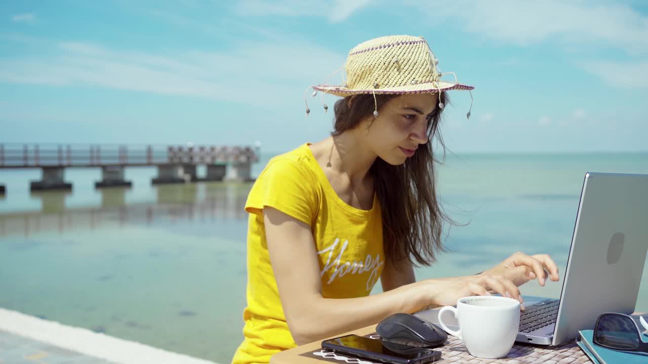 女自由职业者在海边使用笔记本电脑。手在键盘上输入文本，搜索信息视频素材