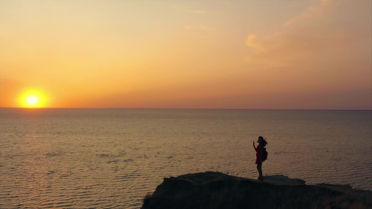 那个美丽的女孩站在山顶，面对着如画的海景视频素材