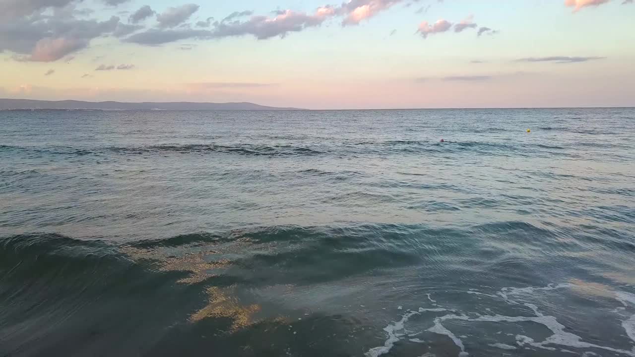 鸟瞰图的海面与蓝色的海浪下日落的天空。视频素材