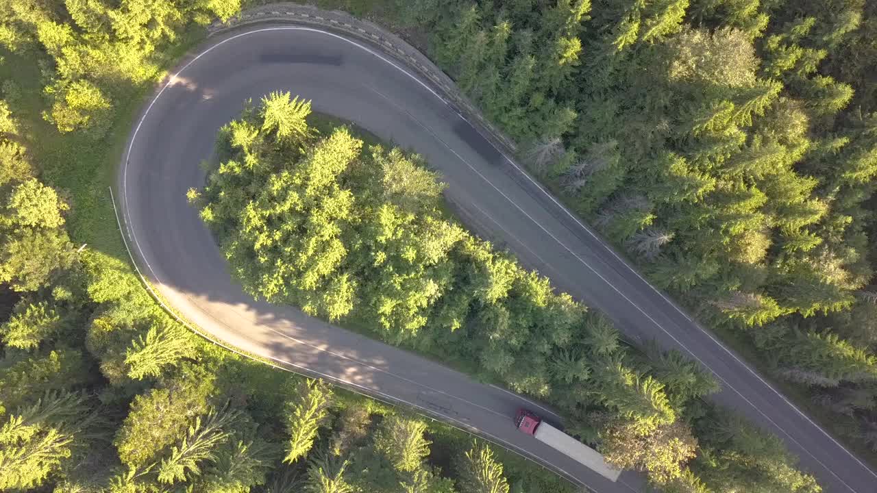 鸟瞰图蜿蜒的道路与割草汽车和卡车在高山口槽密林。视频素材