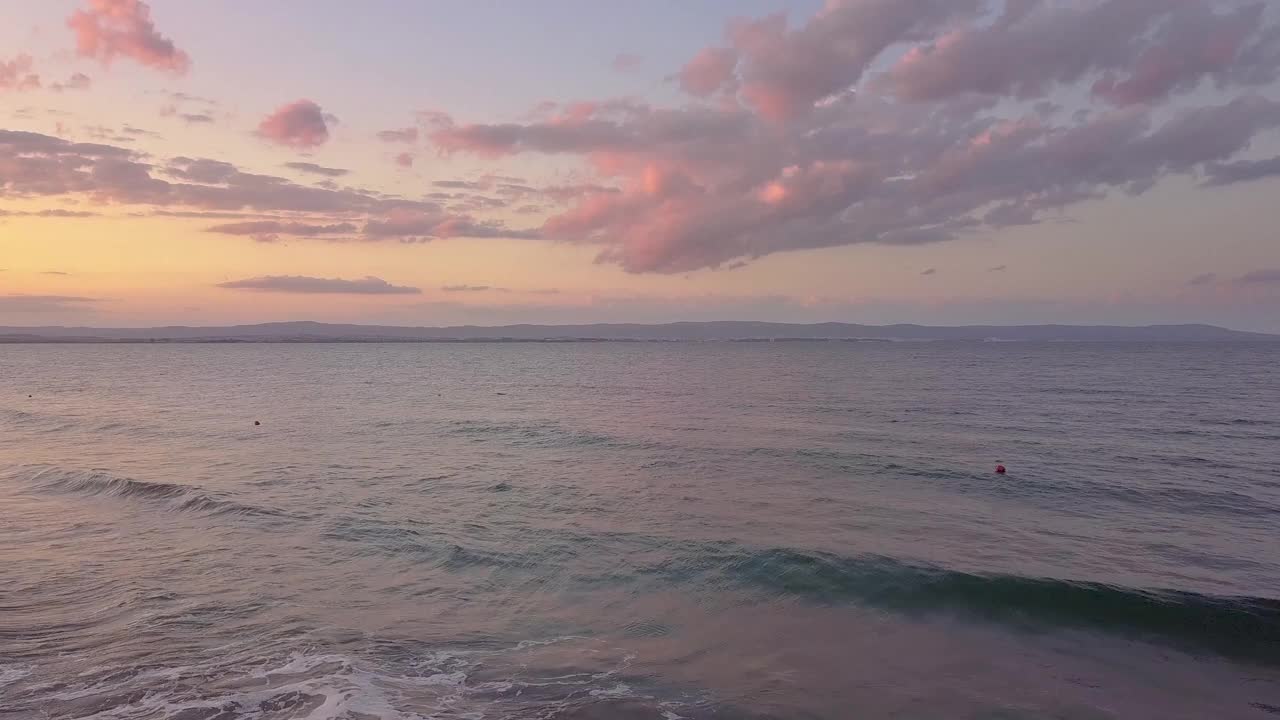 鸟瞰图的海面与蓝色的海浪下日落的天空。视频素材