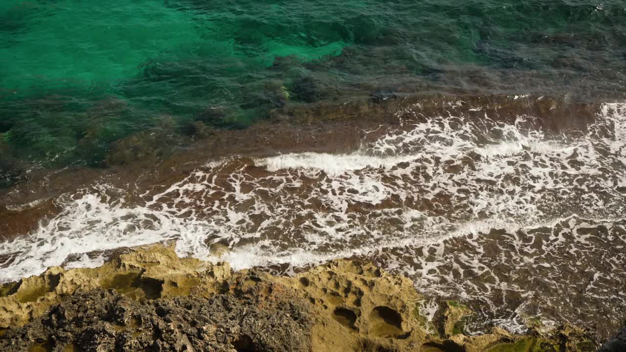 在一个阳光明媚的日子里，小波浪拍打着岩石海岸视频素材