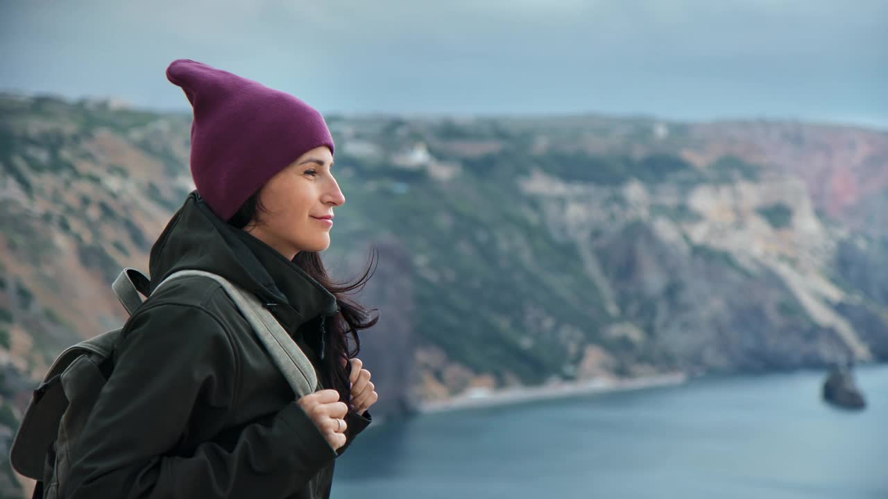 愉快的潮女人旅行背包客站在高崖顶在多风的天气享受自然视频素材