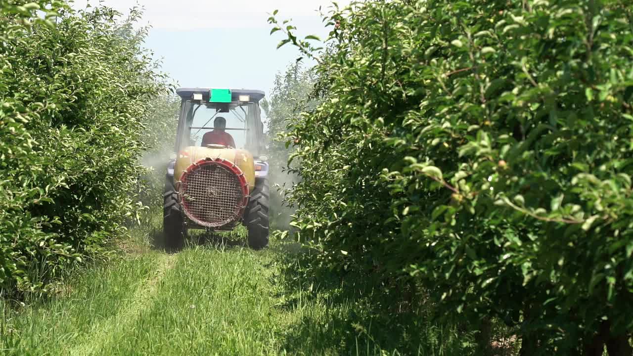 拖拉机向苹果园喷洒的慢动作视频视频素材