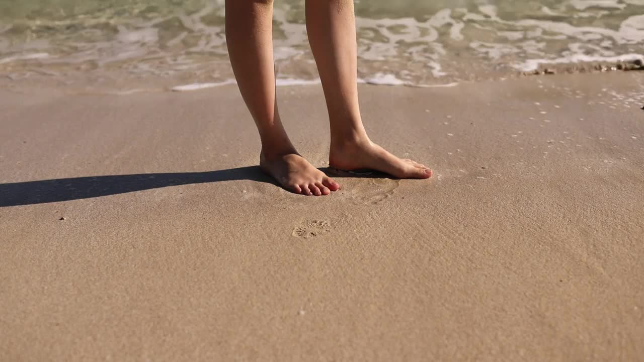 脚被海浪冲掉了。海浪滚在沙滩上洗女人的脚站在潮湿的边缘下阳光近距离。在海上休息视频素材