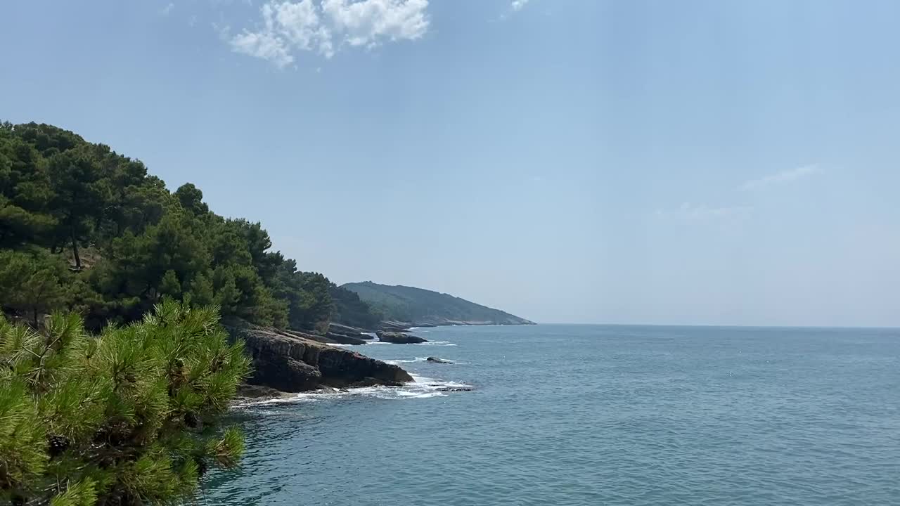 夏日的大海。美丽的地中海海岸岩石景观与针叶松森林。阳光明媚的夏日大自然。蓝色平静的海水。晴朗的天空。风景优美的海岸线。视频素材